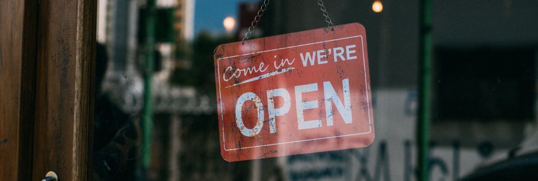 Señal que pone "open" en la puerta de una tienda